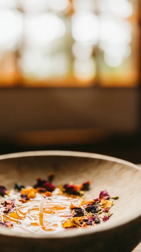 Close-up still life of melted candle wax pooling on a stone altar, dried petals scattered around