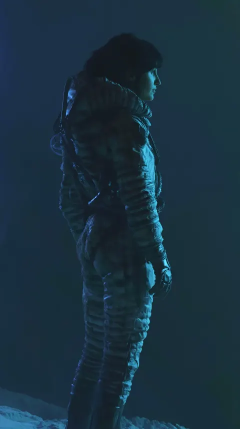 Full body shot of a lone female explorer, standing and turned slightly away from camera