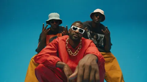 Full body group portrait of three stylish Black hip-hop artists posing together in a studio