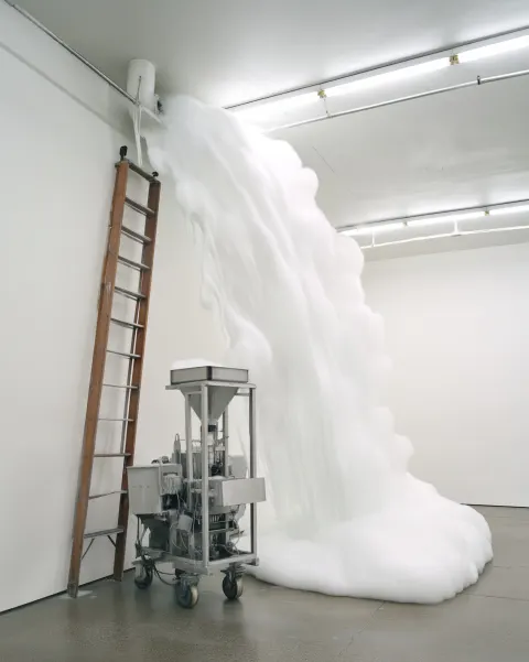 Image depicts a contemporary art installation in an industrial-style gallery space with concrete flo