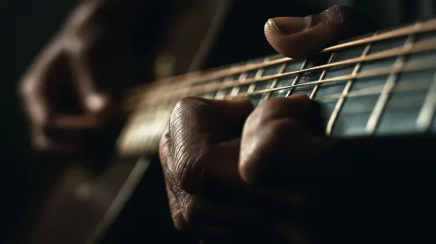 Close-up photograph of human hands playing an acoustic guitar