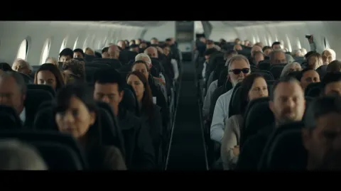 View from front of commercial airplane cabin looking at passengers faces