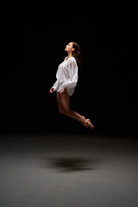 Young Moldovan woman floating slightly above ground in dark void body relaxed