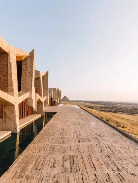 Monumental brutalist palace in the Egyptian desert, overlooking the pyramids of Giza
