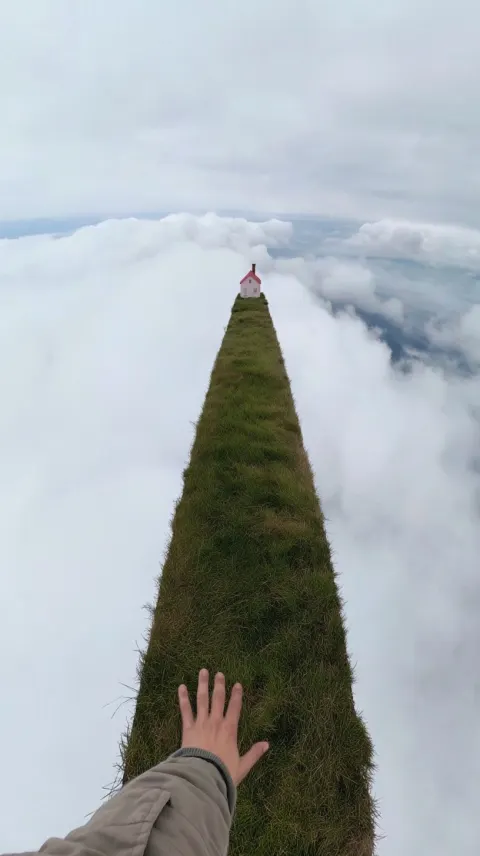 Raw GoPro POV walking along impossibly narrow grass-covered land bridge floating above infinite clou