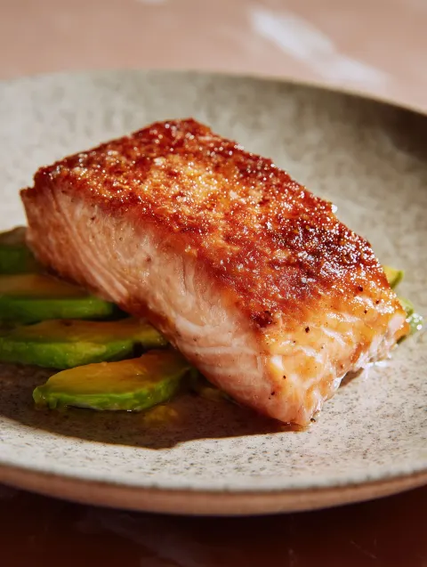Pan-seared salmon with crispy skin, sliced avocado, editorial photo quality