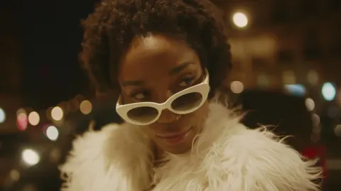 Une jolie femme noir de 27 ans, avec des lunettes de soleil blanche design