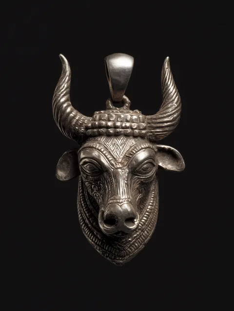 A sumerian zoroastrian silver pendant of the head of a royal charging bull