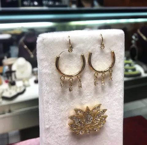 A pair of gold hoop earrings with small diamonds hanging from the bottom