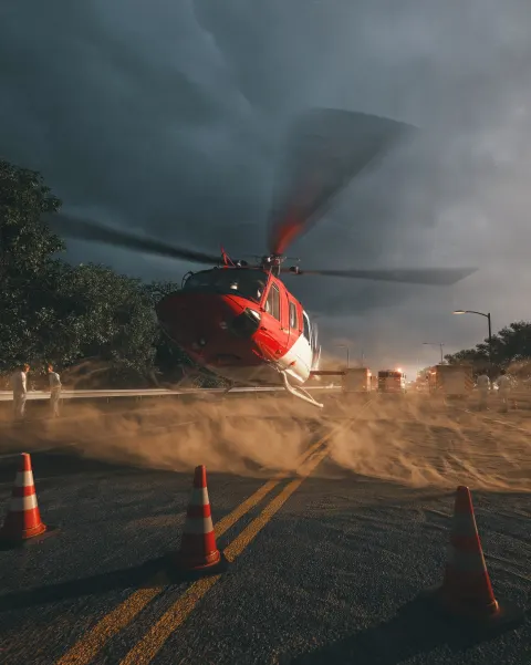 Red and white emergency rescue helicopter landing on a closed highway