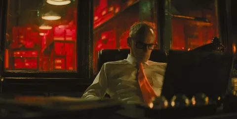 A cinematic still of an office desk with the boss sitting behind it. he is middle-aged and balding