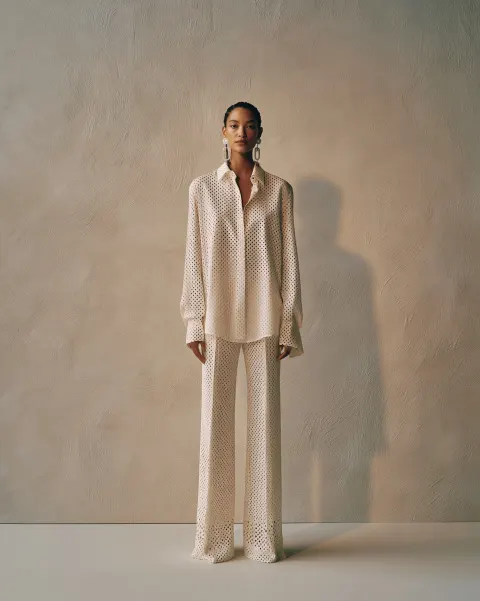 A full-body studio shot features a young beautiful top model standing against a textured