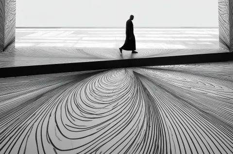 Black and white photograph of an arabic man walking on the edge of an enormous abstract pattern
