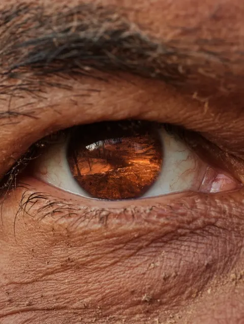 Extreme close-up of a geologist's eye filling the entire frame, dust on skin, sun-worn face