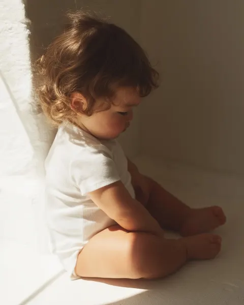 Candid snapshot of a chubby 18-month-old East Asian European mixed toddler, soft wavy brown hair