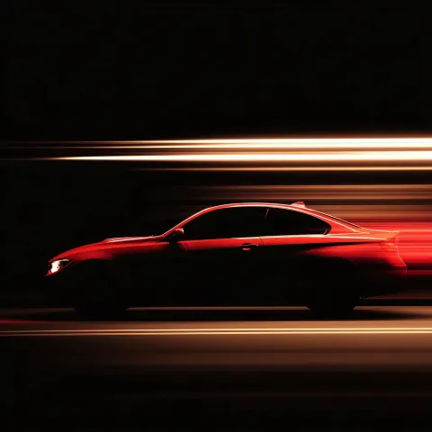 Panning photograpny of a red car silhouette in close-up on a black background, with blurred motion