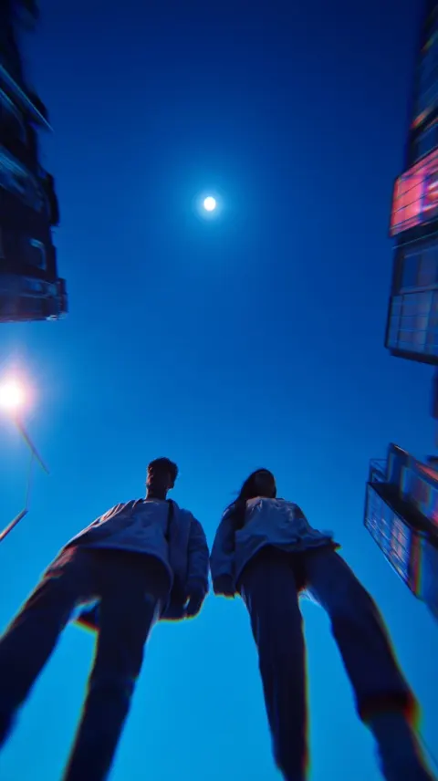 Ultra low angle view from near the ground between and behind two young people walking side by side a