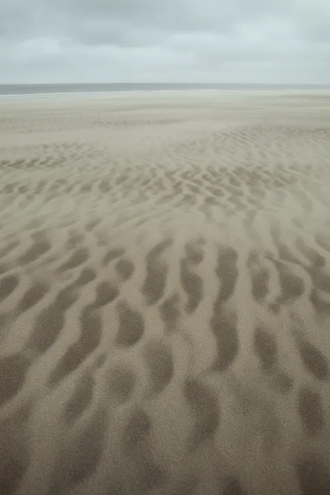 A photograph of wind-shaped sand patterns across a beach.