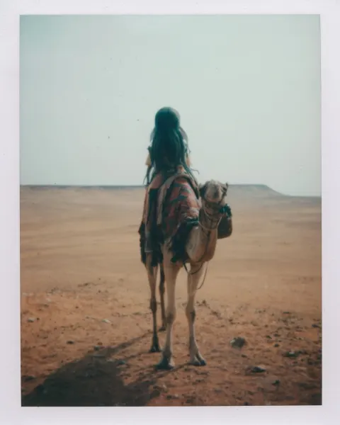 Cthulhu as a berdy tourist riding a camel, egyptian desrt