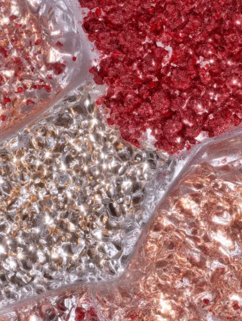 Close-up view of a transparent umbrella as thick red gel droplets splash and scatter upon contact. T