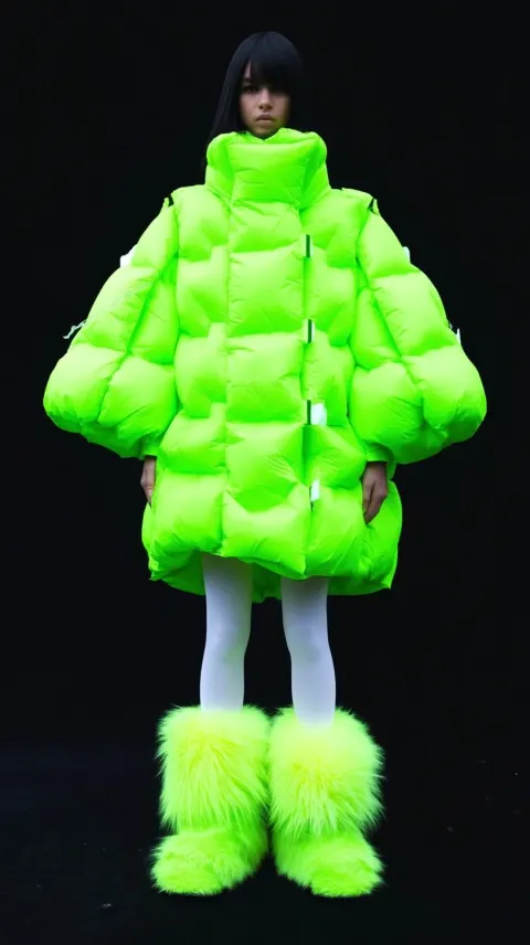 A full-body studio photograph of an inflatable, neon green puffer jacket, white tights