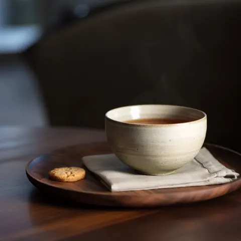 Eye-level shot of a hand-thrown ceramic cup of tea with subtle steam rising