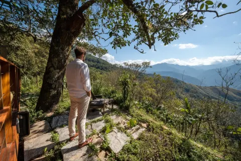 Handsome man standing in front of his treehouse on the top floor, full body shot