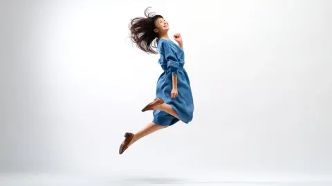 Full body of a young Japanese woman, mid-air jumping pose, moving from left to right