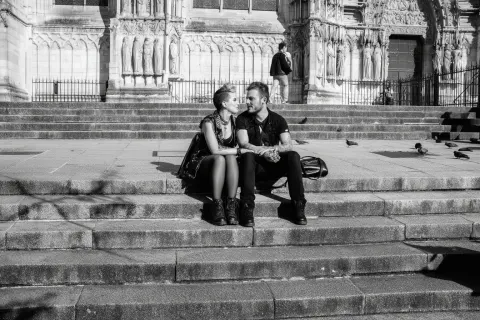 Black and white street photography of a punk couple siiting on the steps of a cathedral in france