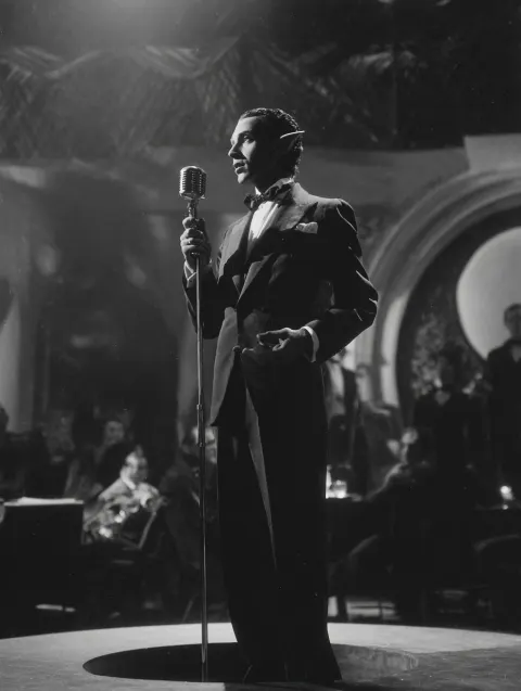 1930s black and white film noir movie still shot. Classy brown skin elf male singer on stage. Dark w