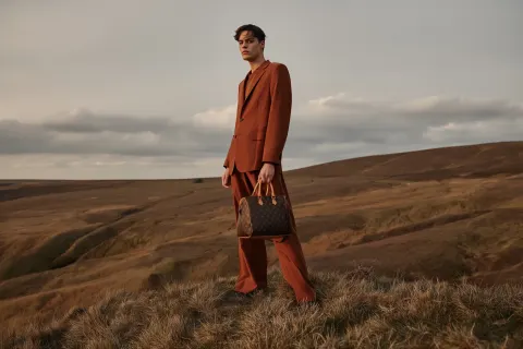 High fashion cinematic composition, same grassy hill peak with rolling terrain and soft cloudy sky