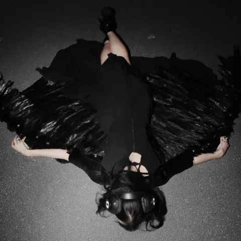 Model woman wearing black dress, laying face first on the ground, overhead centered shot