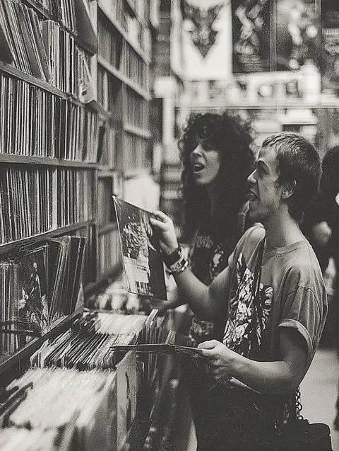 A black-and-white photograph of two people in an old record store