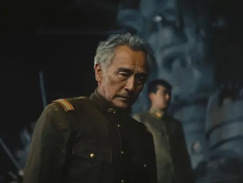 Film still, A sokitary old man is approaching the space battleship. The old man has gray hair and we