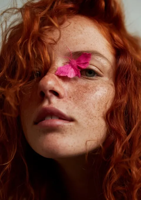 A close-up of the face of an adorable young girl with red hair and light skin