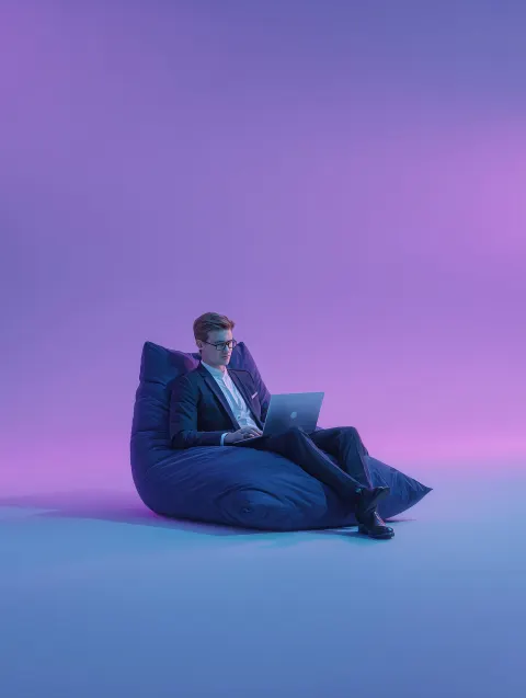 An isolated businessman sitting on a lazybag with laptop. A young professional Businessmen sitting a